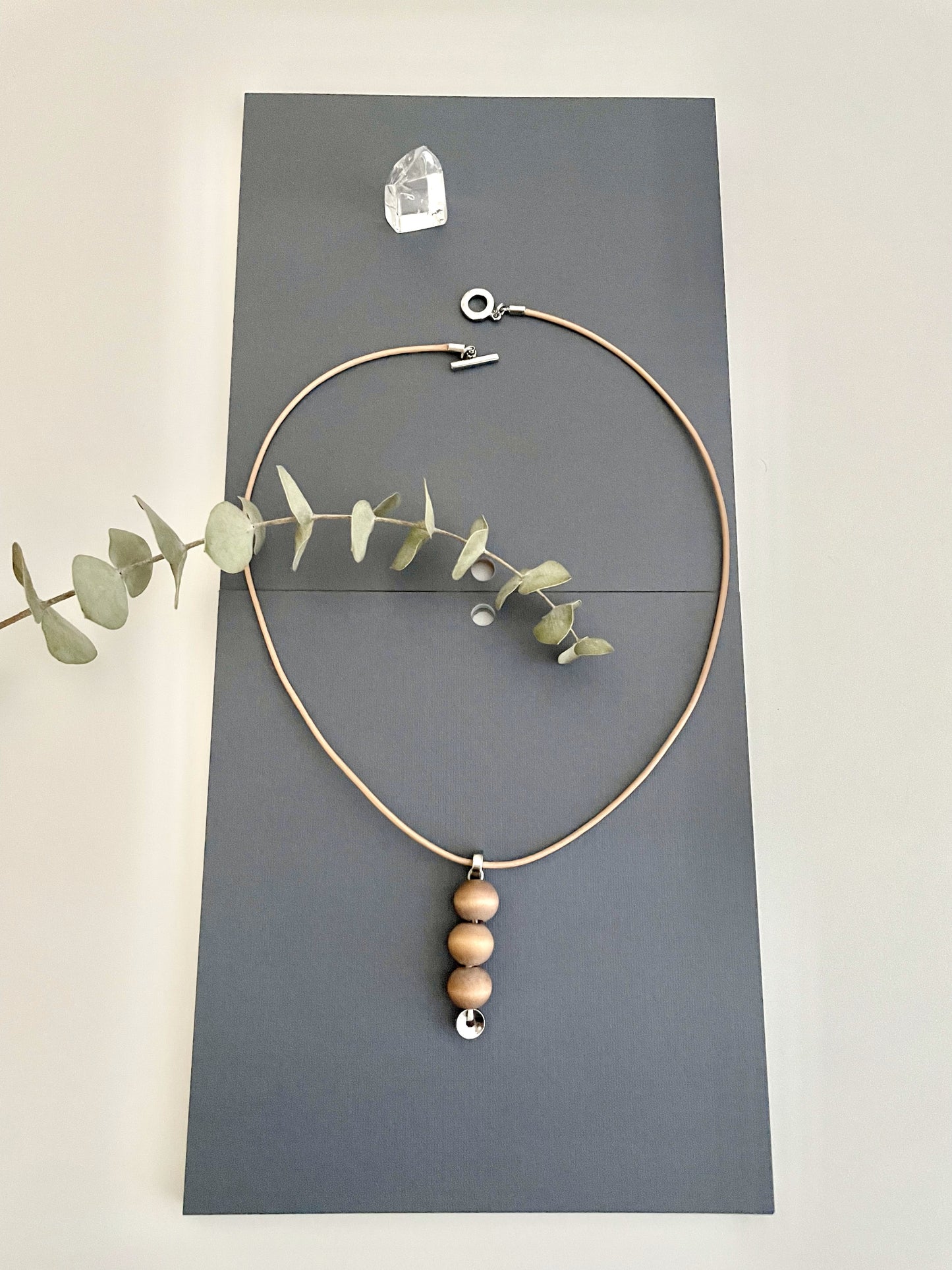 A unique minimalistic with three wood beads, leather cord, and a round toggle clasp