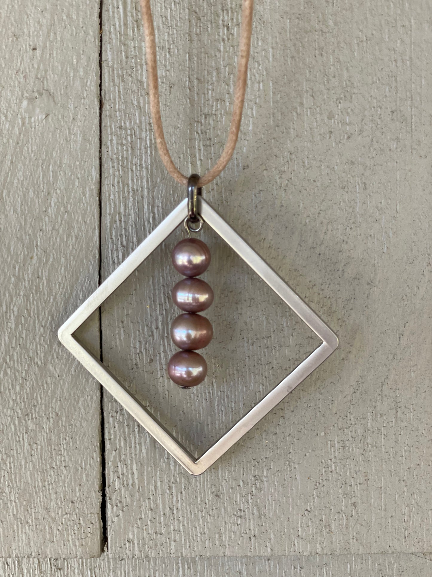 A unique necklace with a stack of river pearls within a matte metal frame