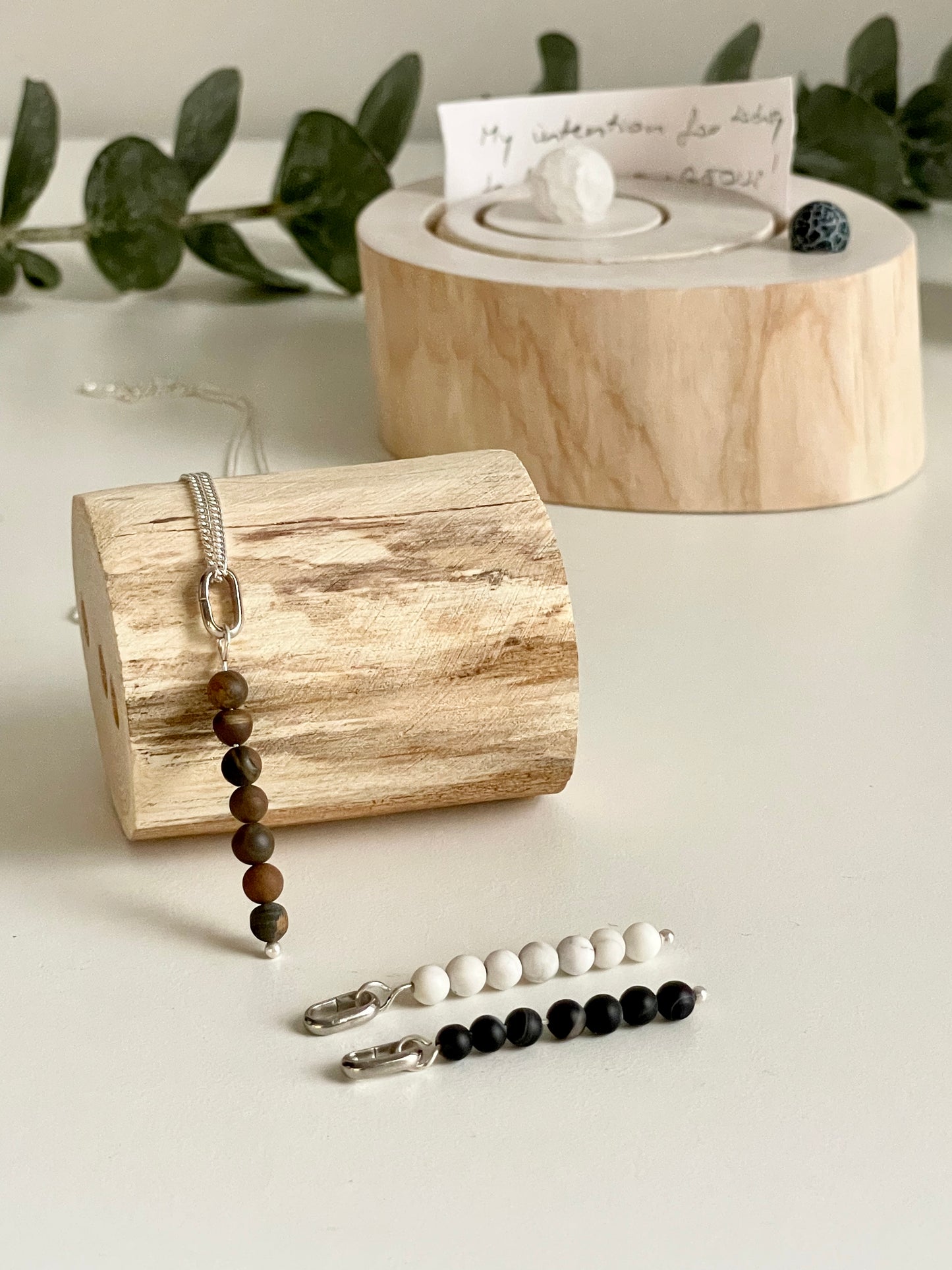 An interchangeable pendant with three beads of howlite, tigers eye, and black agate crystals